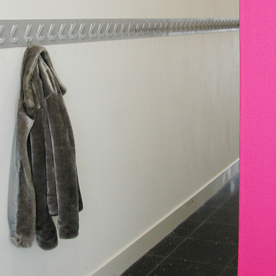Manon’s grijze jasje hangt eenzaam aan een van de vele haken achter de zuurstokroze muur 